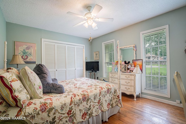 bedroom with ceiling fan, a textured ceiling, light wood-type flooring, and a closet