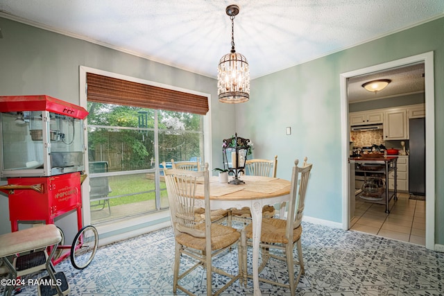 tiled dining space with a notable chandelier, crown molding, and a textured ceiling