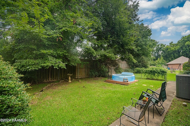 view of yard with a pool and central AC