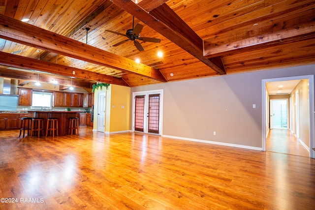 unfurnished living room featuring wooden ceiling, light hardwood / wood-style floors, sink, ceiling fan, and vaulted ceiling with beams