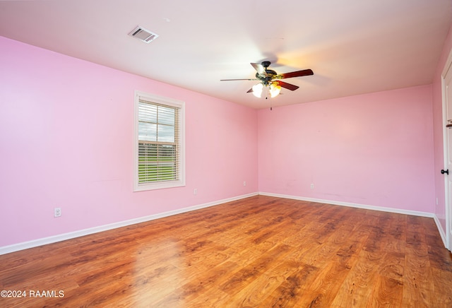 empty room with visible vents, baseboards, wood finished floors, and a ceiling fan