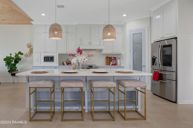 kitchen featuring appliances with stainless steel finishes, white cabinets, a kitchen bar, and decorative light fixtures