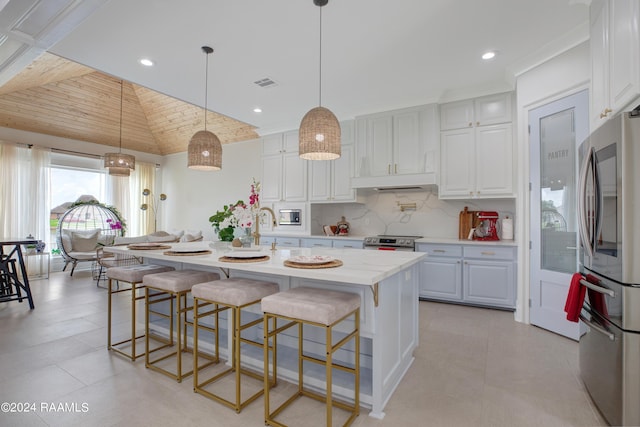 kitchen with white cabinetry, a center island with sink, a kitchen breakfast bar, pendant lighting, and stainless steel appliances