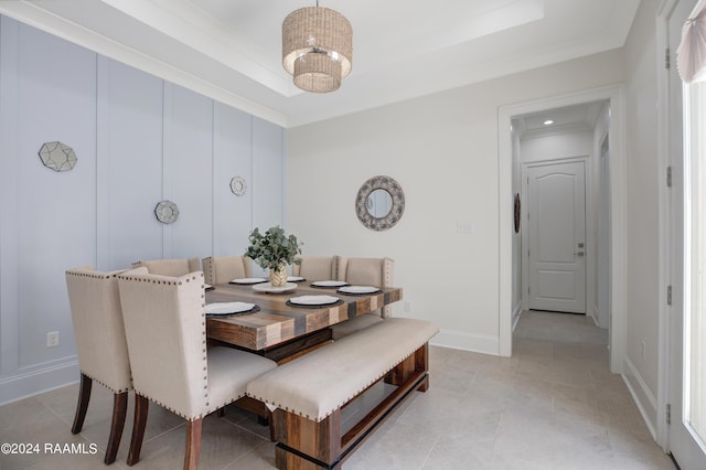 dining area with a notable chandelier, a tray ceiling, and ornamental molding