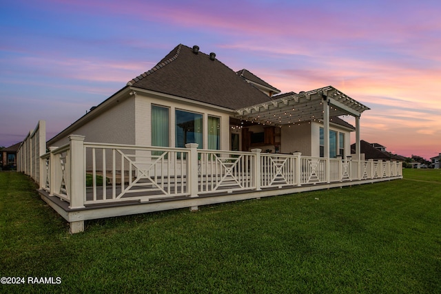 back house at dusk with a pergola and a yard