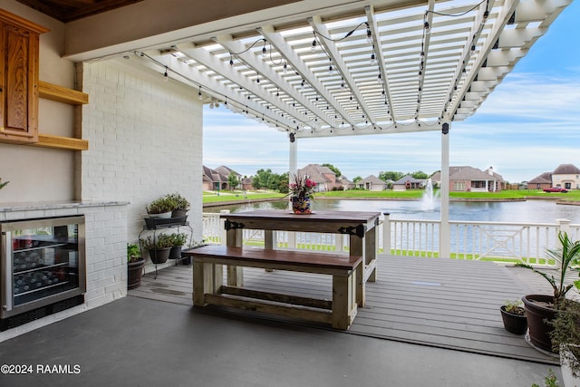 deck with wine cooler, a pergola, and a water view