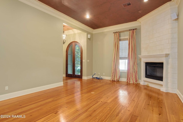 unfurnished living room featuring light hardwood / wood-style flooring, ornamental molding, and a large fireplace