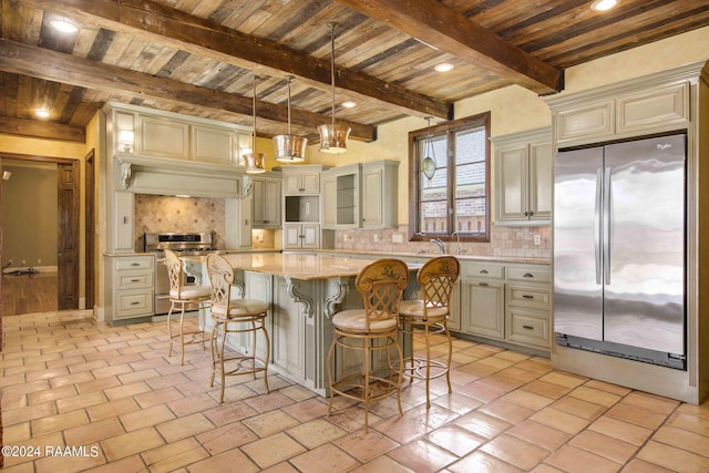 kitchen featuring stainless steel appliances, decorative backsplash, beam ceiling, cream cabinetry, and a center island