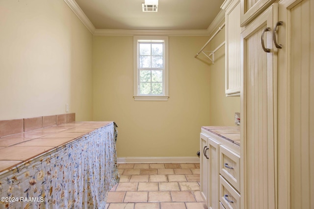 clothes washing area with light tile patterned flooring and ornamental molding