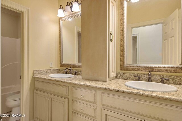 bathroom with double vanity, toilet, and a sink