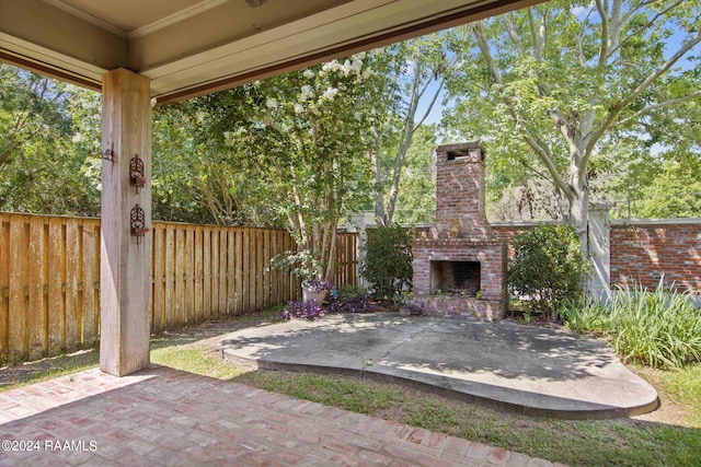 view of patio with fence and an outdoor brick fireplace