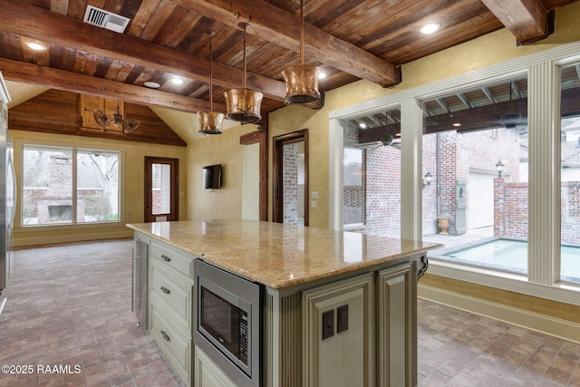 kitchen featuring light stone counters, stainless steel microwave, plenty of natural light, and wood ceiling