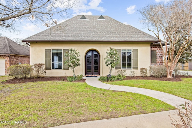 view of front of home with a front lawn, stucco siding, french doors, and a shingled roof