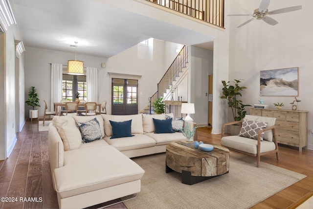 living room with french doors, ceiling fan, hardwood / wood-style floors, and a towering ceiling