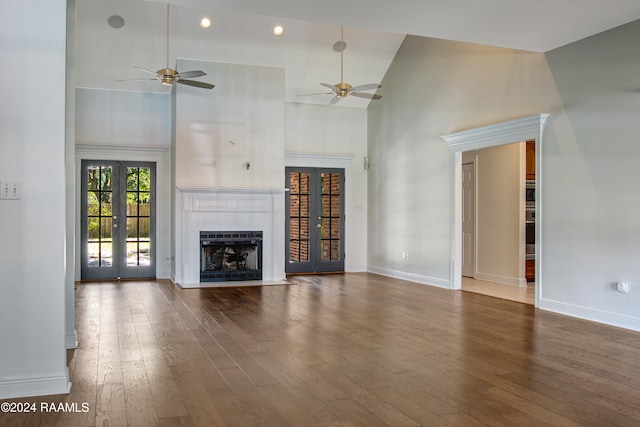 unfurnished living room featuring a tile fireplace, ceiling fan, dark hardwood / wood-style flooring, and french doors