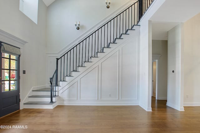 foyer entrance featuring a towering ceiling and light hardwood / wood-style flooring