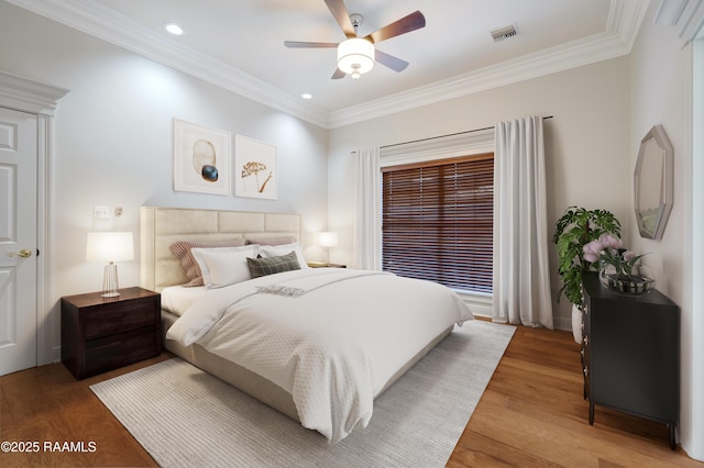 bedroom featuring crown molding, wood-type flooring, and ceiling fan