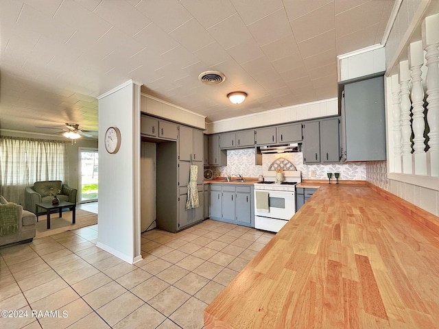 kitchen featuring sink, gray cabinetry, light tile patterned floors, white gas range, and butcher block counters