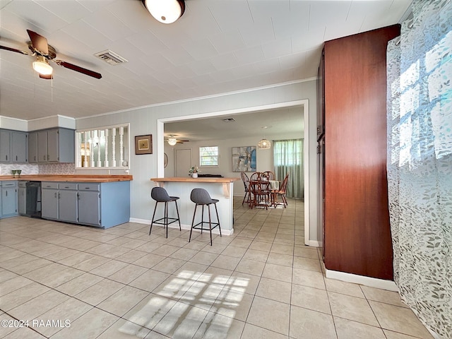 kitchen featuring black dishwasher, tile patterned flooring, a kitchen breakfast bar, ornamental molding, and gray cabinets