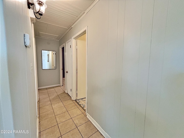 hallway featuring wooden walls and light tile patterned flooring