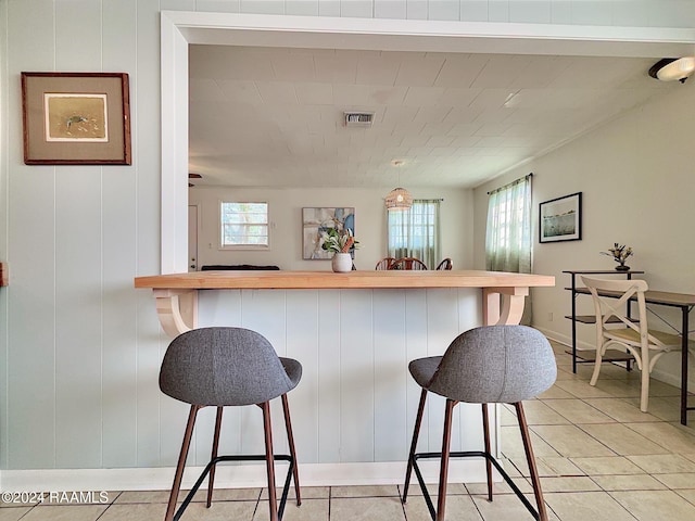 kitchen featuring a kitchen breakfast bar, plenty of natural light, and light tile patterned flooring