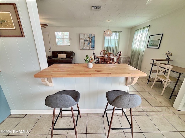 kitchen featuring butcher block countertops, a breakfast bar area, and light tile patterned flooring