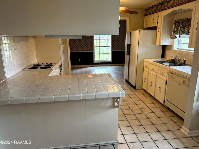 kitchen featuring tasteful backsplash, white appliances, sink, tile counters, and kitchen peninsula