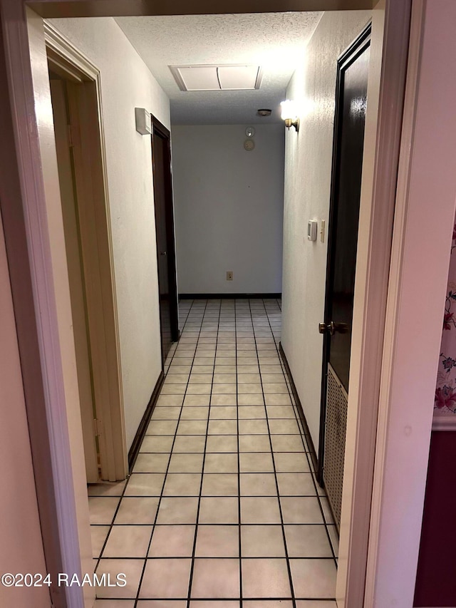 hall with a textured ceiling and light tile patterned floors