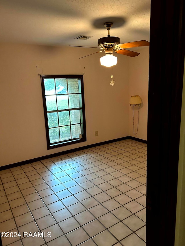 unfurnished room featuring light tile patterned flooring, ceiling fan, and a textured ceiling