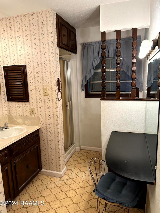 bathroom with vanity, a textured ceiling, and a shower with door