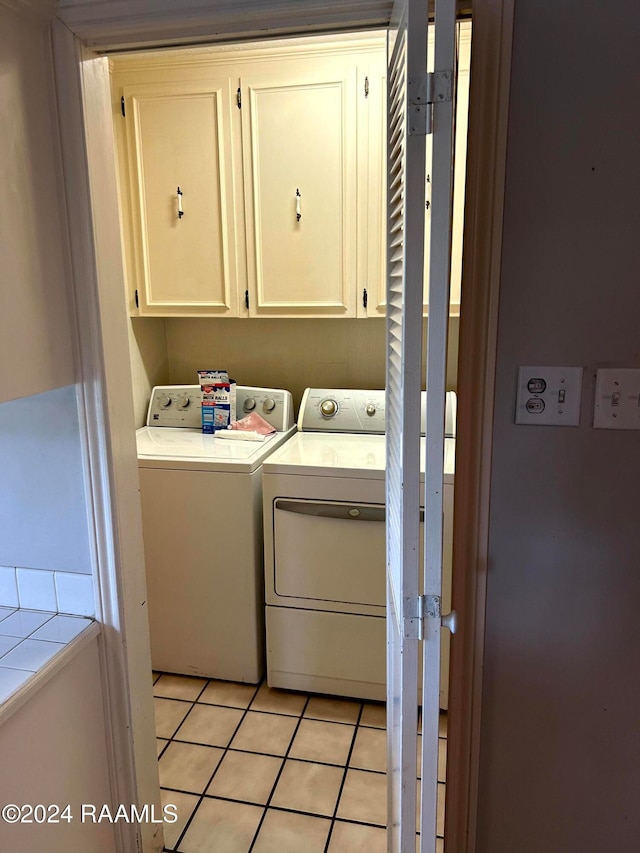 laundry area with cabinets, washing machine and dryer, and light tile patterned floors