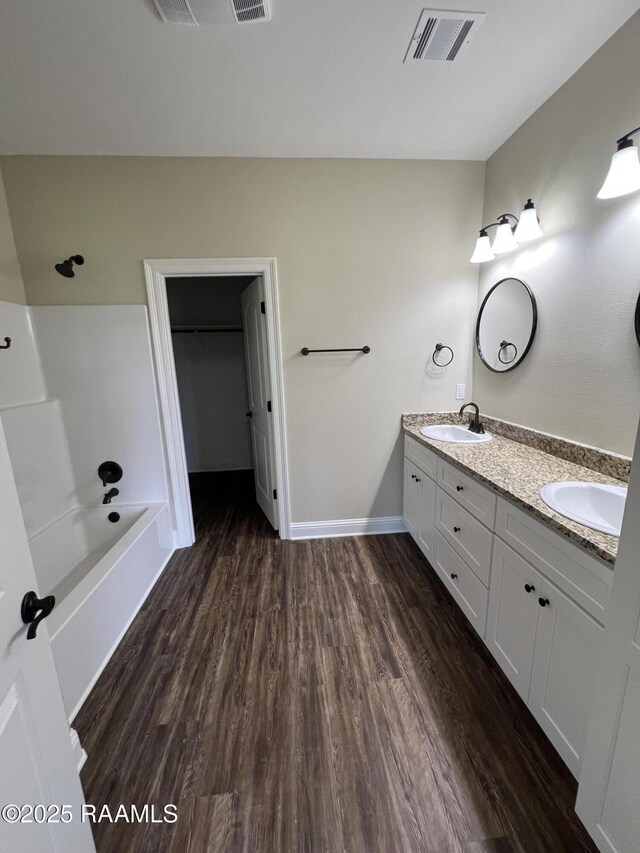 284 Sugarland Cir, Opelousas, LA 70570 - full bathroom featuring double vanity, wood finished floors, a spacious closet, baseboards, and  shower combination