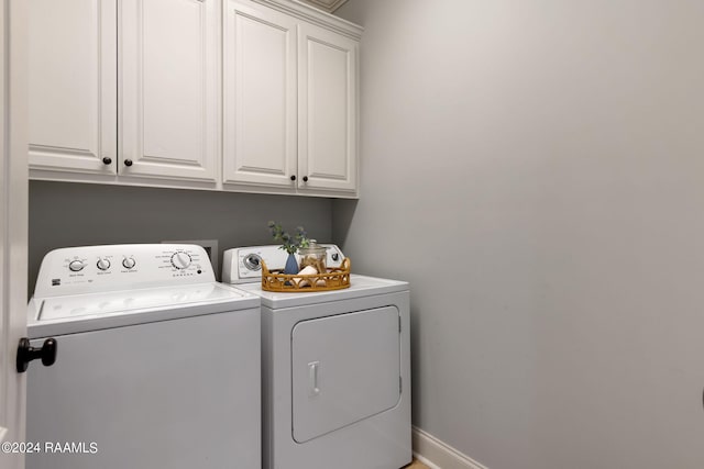 clothes washing area with cabinets and washer and dryer