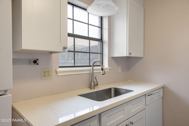 kitchen with dishwasher, light stone countertops, white cabinetry, and sink