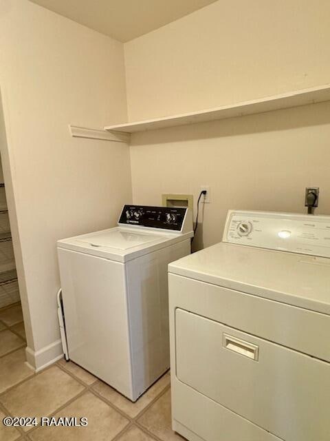 clothes washing area featuring light tile patterned flooring and washer and dryer