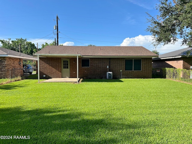 rear view of house with central AC, a lawn, and a patio area