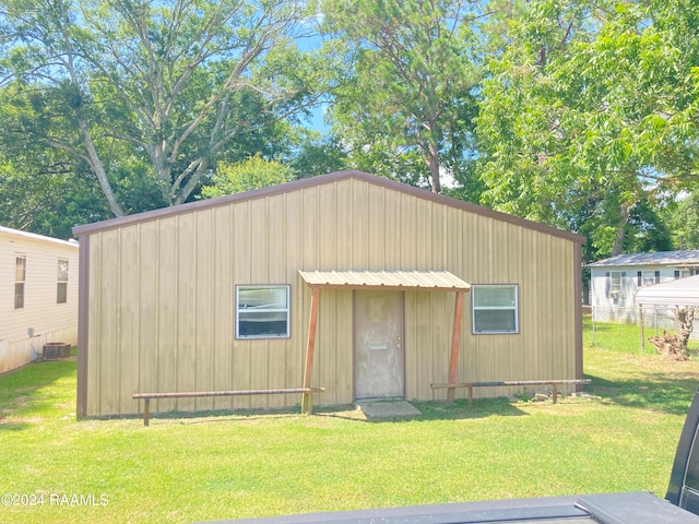 view of outdoor structure featuring a lawn and cooling unit