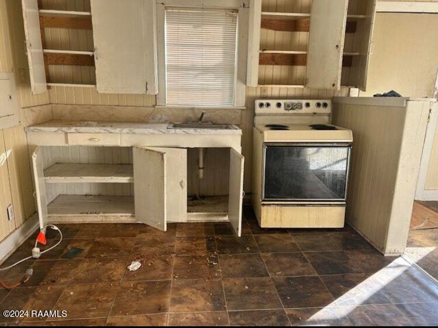 kitchen featuring electric range, sink, and dark tile patterned flooring