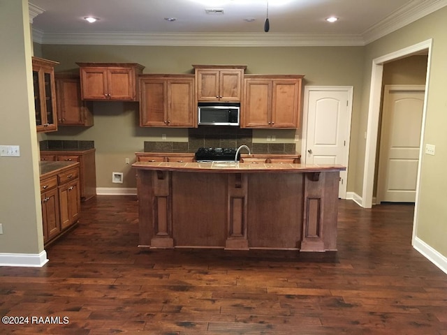 kitchen featuring sink, tasteful backsplash, ornamental molding, dark hardwood / wood-style floors, and an island with sink