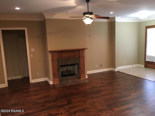 unfurnished living room featuring ornamental molding, dark wood-type flooring, a tile fireplace, and ceiling fan