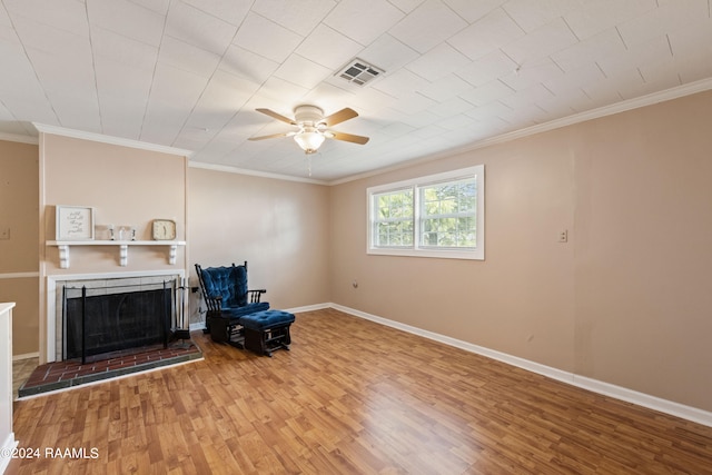 interior space with light hardwood / wood-style floors, a brick fireplace, ornamental molding, and ceiling fan