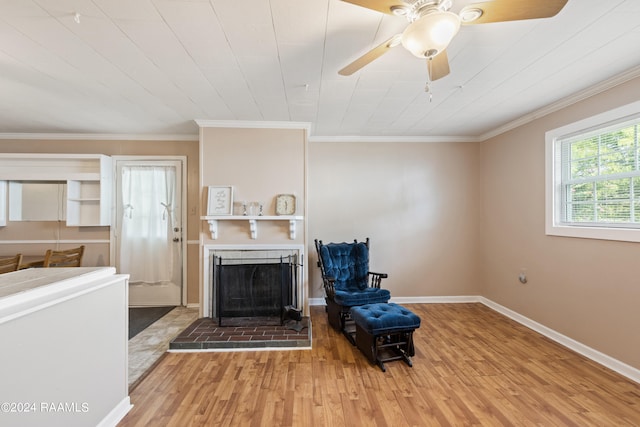 living room featuring ornamental molding, light hardwood / wood-style flooring, a brick fireplace, and ceiling fan