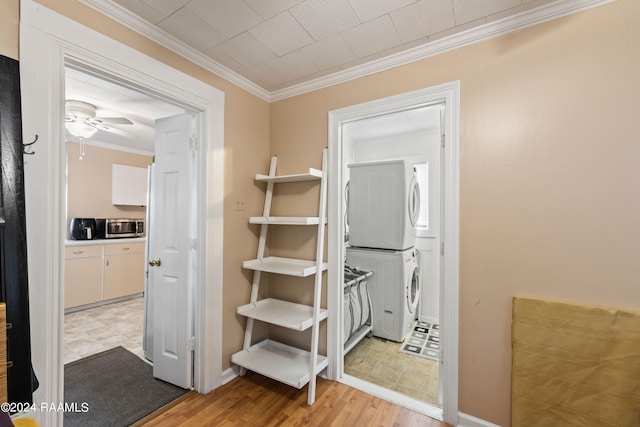 hall featuring ornamental molding, stacked washing maching and dryer, and light tile patterned floors