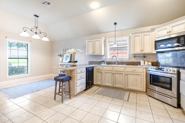 kitchen with light tile patterned flooring, stainless steel appliances, sink, a breakfast bar area, and kitchen peninsula