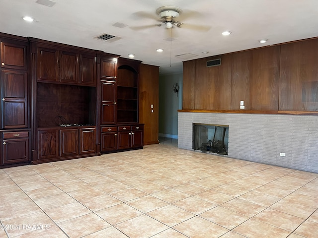 unfurnished living room with ceiling fan, light tile patterned flooring, and a fireplace