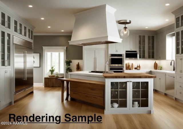 kitchen featuring white cabinets, custom range hood, light wood-type flooring, and stainless steel appliances