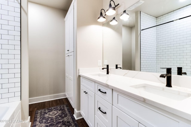 bathroom with double vanity, wood finished floors, baseboards, and a sink