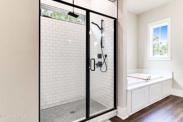 full bathroom featuring baseboards, wood finished floors, a garden tub, and a stall shower