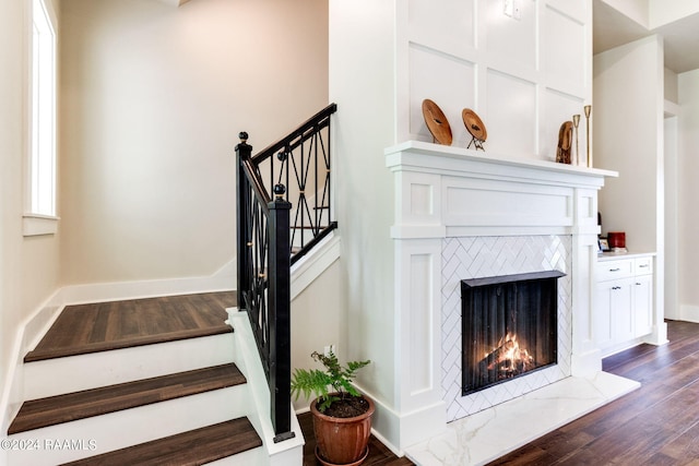 stairs featuring a premium fireplace, baseboards, and wood finished floors