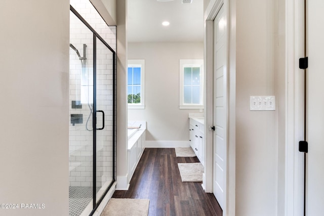 full bathroom featuring vanity, wood finished floors, baseboards, a shower stall, and a bath